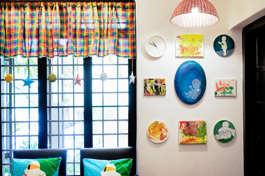 A wall next to a window with several artworks hung together - Beautiful Homes