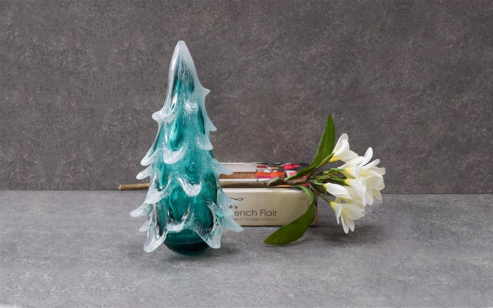 Frost covered turquoise Christmas tree crafted from thick glass, book and flower as d&eacute;cor