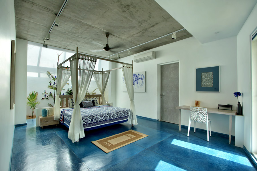 Monochromatic modern bedroom with indigo floor, spare art pieces hung on the walls and concrete ceiling - Beautiful Homes