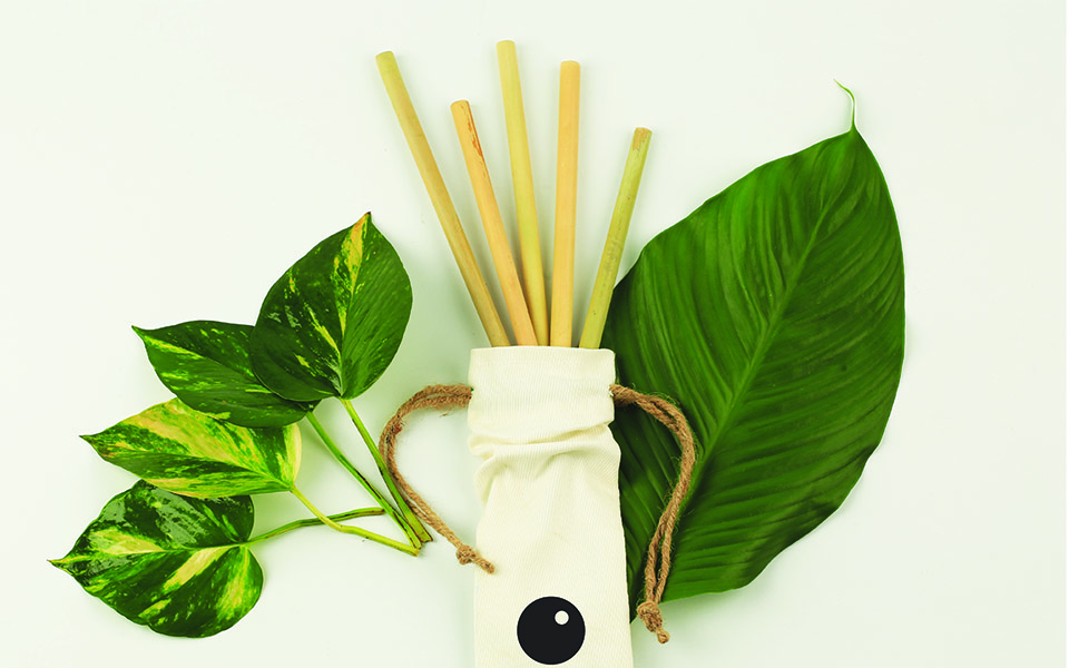 Bamboo straws placed in a cloth bag with leaves around it
