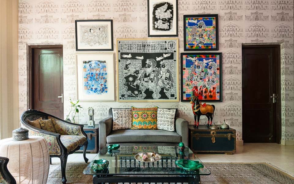 Living room in Delhi with a lot of art works, two antique trunks, a horse figure and a beige sofa
