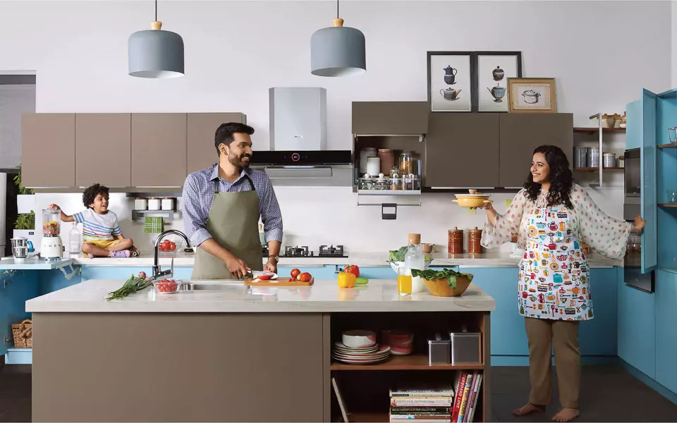 A family cooking together in an open kitchen with an island kitchen, with brown coloured cabinets