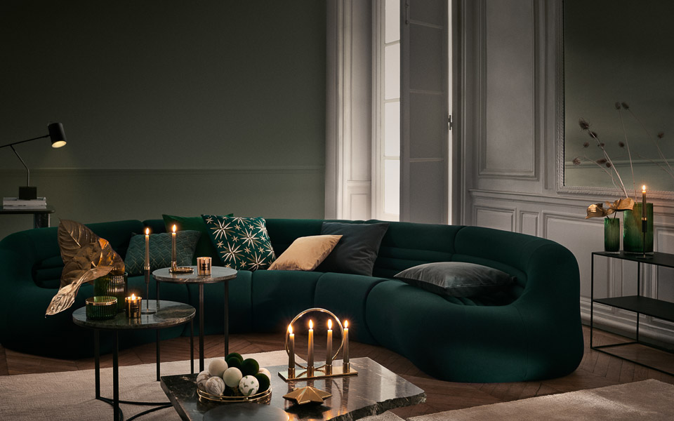 Green living room in dark tones, cushions in shades of green and pink, golden d&eacute;cor pieces and granite centre tables