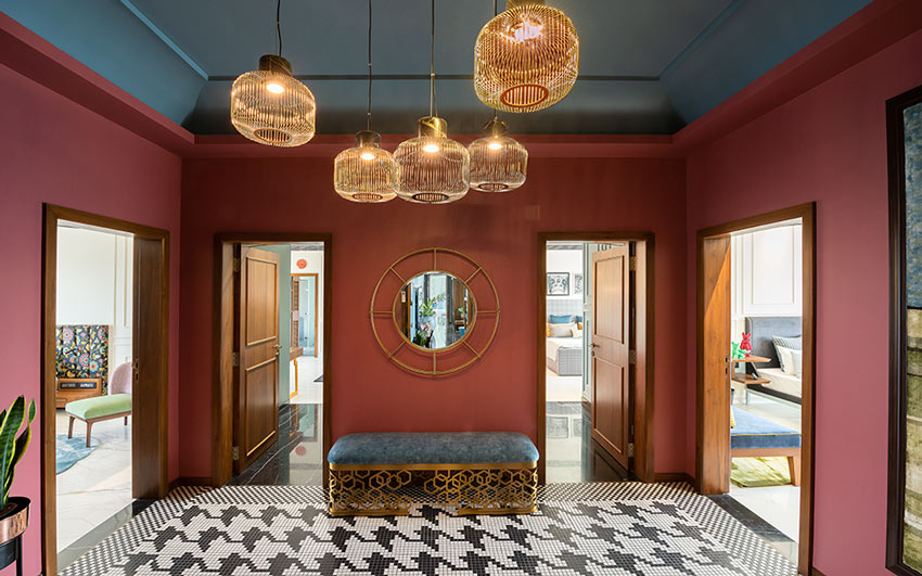 A foyer with access to four rooms with black and white patterned tiles, a bench and a golden framed mirror