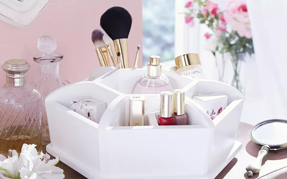 Make up products like brushes, lipstick etc kept  in a organiser on a table