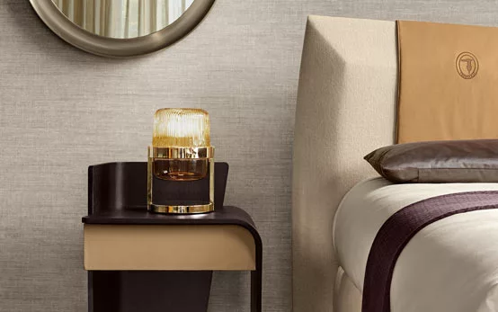 Modern bedroom side table in black and wood next to bed with cream and plum tones
