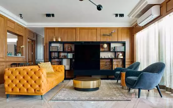 Black elegant TV unit with bookshelves set against wood pannelled walls and Persian rug