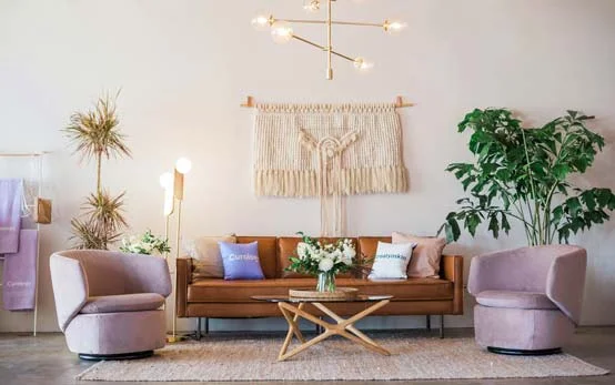 Stylish bohemian living room with leather couch, lilac armchairs and macrame accents