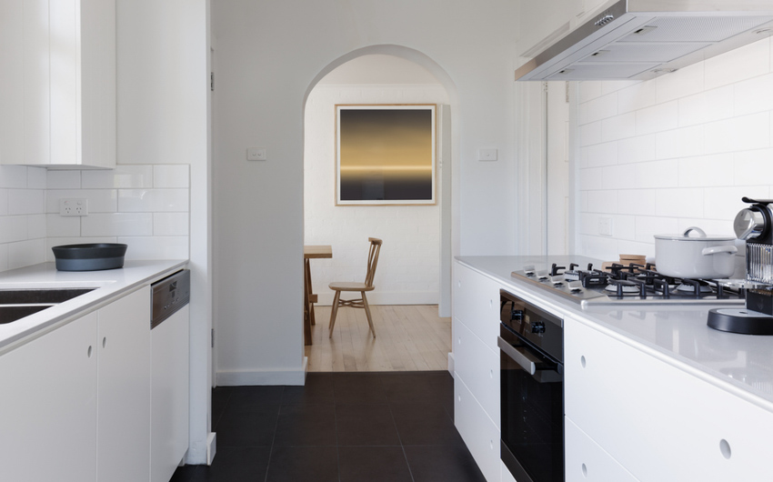 Kitchen arch design optically separating two rooms, all-white walls and furniture