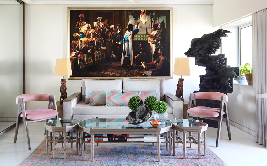 Living room with a white sofa, glass coffee table, two identical pink chairs and a large artwork on the wall behind the sofa