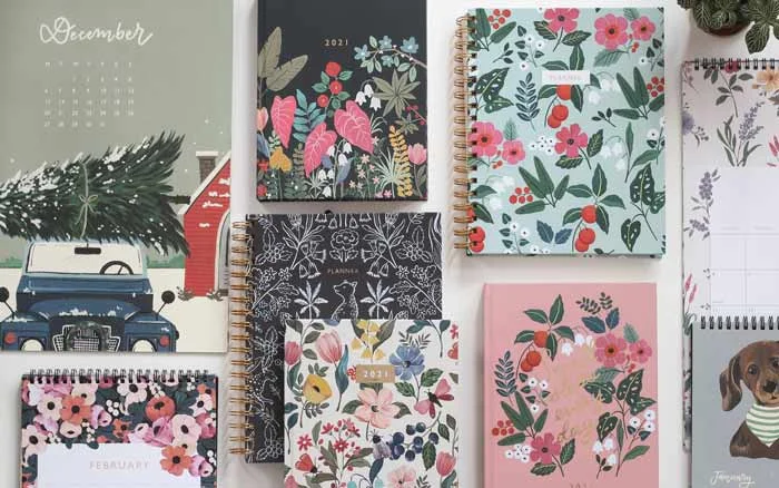 A number of books, a calendar and planners with with floral prints as covers placed on a flat surface