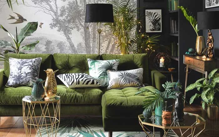 A living room with a green L shaped sofa, white cushions, planters, and a small lights