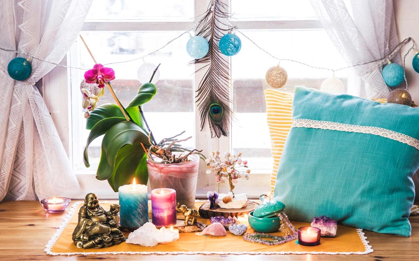 A meditation area with colourful candles, a couple of cushions, some string lights and a plant