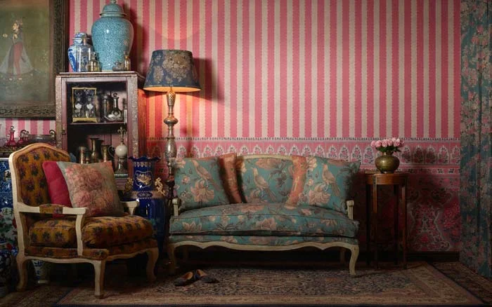 A living room with a pink striped wallpaper and a blue sofa