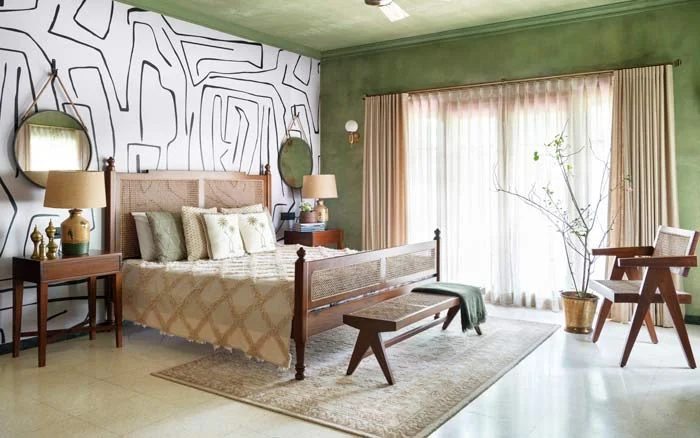 A green bedroom with a white graphic wall and a rattan bed