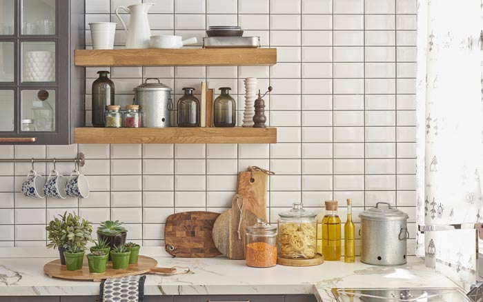 A kitchen with white tiles and wooden shelves