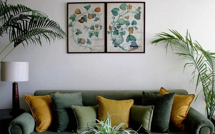 A room with a green sofa and a couple of wall arts