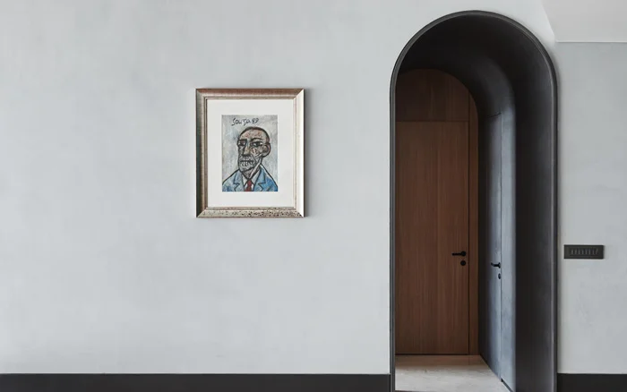 A grey wall with a painting and black skirting