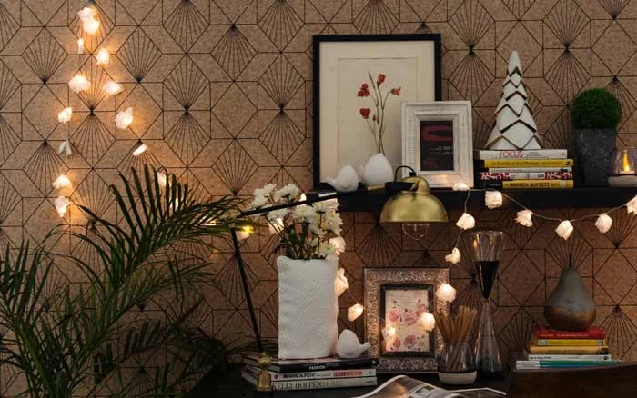 A string of fairy light across some artefacts places in front of a wallpapered wall