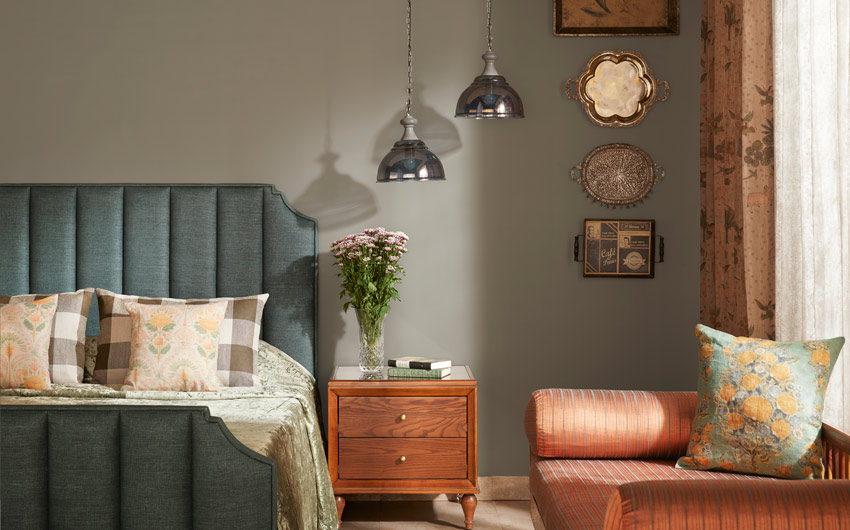 A bedroom with a bed which has a headboard and a small orange sofa next to it