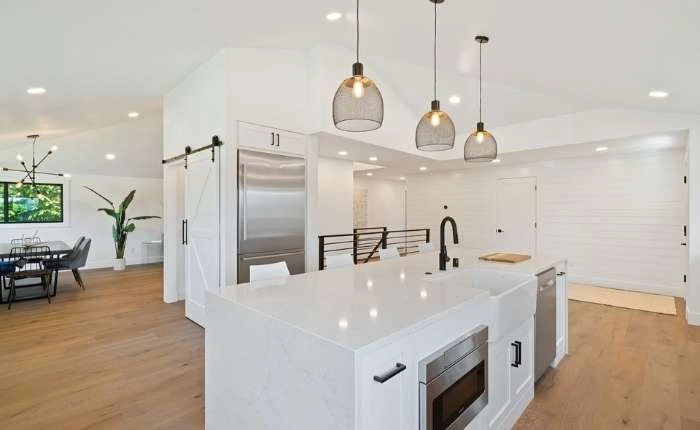 Spacious &amp; all white modular kitchen design with pendant lights &amp; wooden flooring - Beautiful Homes