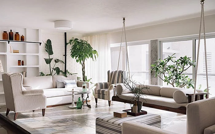 A living room with a white sofa set and plants