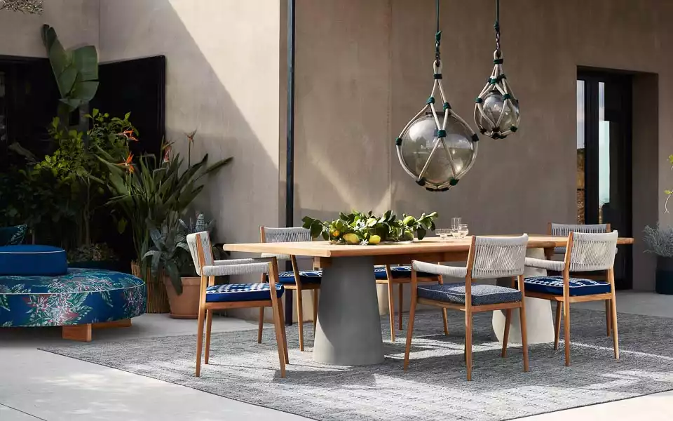Teak wood dining table placed on a grey clay pillar, royal blue seating area,  bulb-like pendant lamps